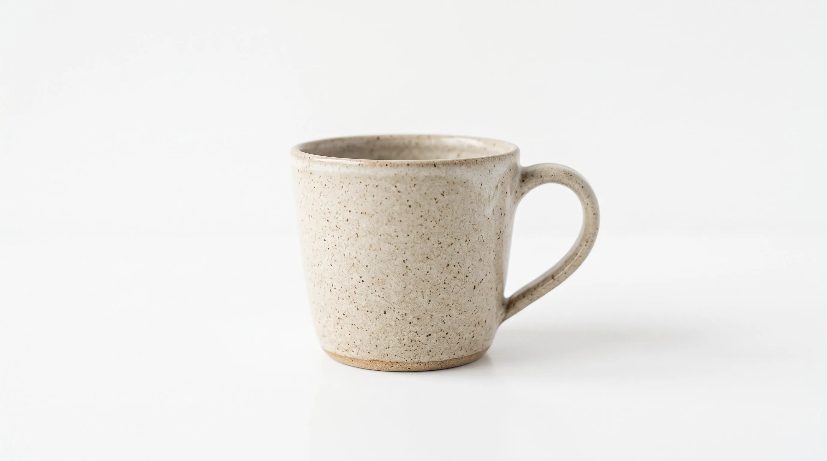 A speckled ceramic mug photographed on a plain white background, an example of clean e-commerce product photography